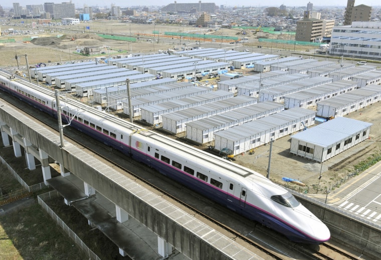 Image: The Shinkansen, or bullet train, is seen speeding past temporary houses for survivors of the earthquake and tsunami, in this photo taken by Kyodo in Sendai